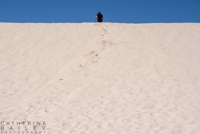Man running up a sand dune | Catherine Bailey Photography