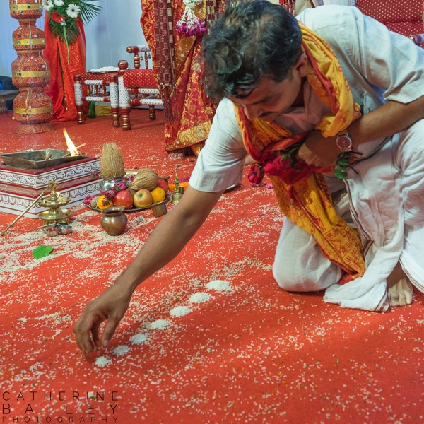 Brahmin priest laying rice at ceremony | Catherine Bailey Photography